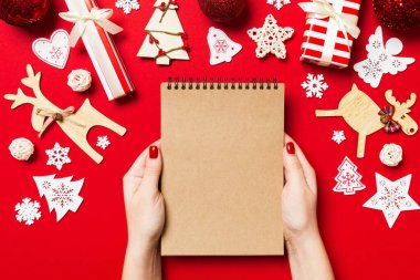 Kadın elinin rengarenk arka planda notlar aldığına dair üst görünüm. Yeni yıl süslemeleri ve oyuncakları. Noel zamanı konsepti.