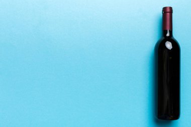 Renkli masada bir şişe kırmızı şarap. Düz konum, üst görünüm kopyalama alanı.