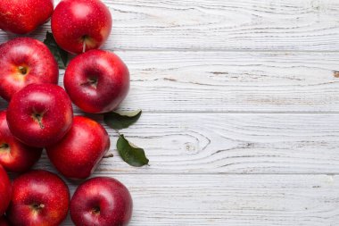 Tahta masada yeşil yapraklı taze kırmızı elmalar. Ahşap arka planda. Metin için üst görünüm boş alanı.