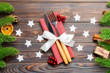 Ahşap arka plandaki şenlikli peçetedeki çatal bıçakların en üst görüntüsü. Kurutulmuş meyve ve tarçınlı Noel süslemeleri. Yeni yıl yemeği konseptini kapat.