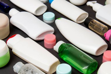 Renkli arka plandaki kozmetik ürünleri için farklı boyutlarda şişeler ve kavanozlar. Fotokopi alanı ile yüz ve vücut bakımı kavramı.