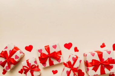 Top view photo of valentine day decorations gift box with red ribbon bow on colored background. Holiday gift boxes with top view.
