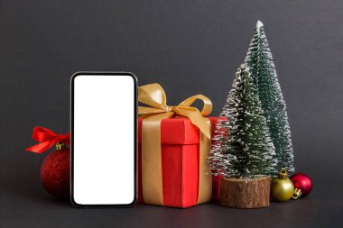 Digital phone mock up with rustic Christmas decorations for app presentation with empty space for you design. Christmas online shopping concept. Tablet with copy space on colored background.