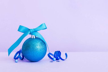 Christmas ball on colored background. decoration bauble with ribbon bow with copy space.