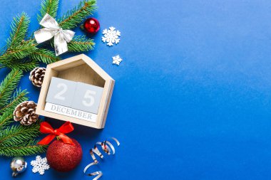 Christmas calendar 25 december. Christmas gift, fir branches, pine cones. Flat lay, top view. New Year decorations on a colored background.