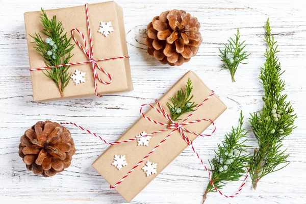 Christmas or New Year presents wrapped in natural colored paper and decorated with traditional Xmas twine and fir twigs on white background.