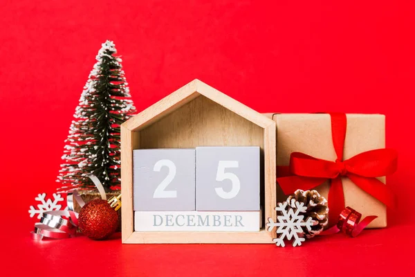 25 december. Christmas composition on colored background with a wooden calendar, with a gift box, toys, bauble copy space.