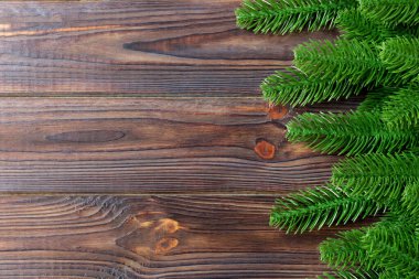 Ahşap zemin üzerinde köknar ağacı dallarından yapılmış çerçevenin üst görüntüsü. Tasarımınız için boş boşluklu Noel kavramı.