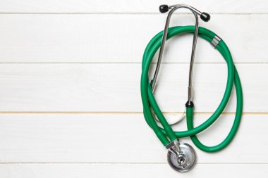 Ahşap arka planda yeşil steteskop manzarası. Tıbbi muayene kavramı. Beyaz ahşap arka planda yeşil steteskopun üst görüntüsü. Tıbbi muayene kavramı.