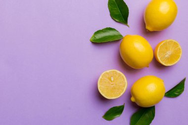 Renkli arka planda yeşil yapraklı taze limonlar, üst görünüm, metin için boşluk.