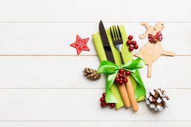 Yeni yıl çatal ve bıçak seti peçeteye. Noel süslerinin ve ahşap arka plandaki ren geyiklerinin en üst görüntüsü. Tasarımınız için boş alanı olan tatil aile yemeği konsepti.