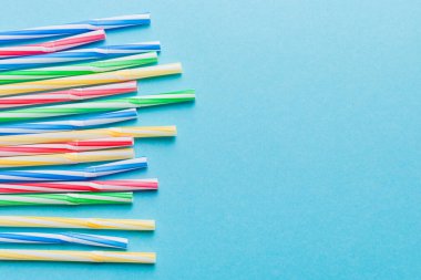 Renkli arka planda renkli plastik pipetler, düz yatış. Metin için Boşluğu Kopyala.