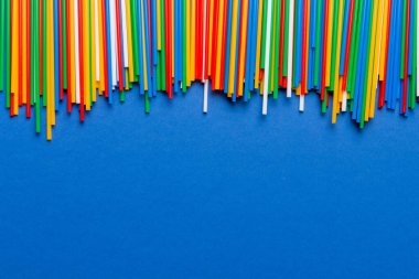 Renkli arka planda renkli plastik pipetler, düz yatış. Metin için Boşluğu Kopyala.