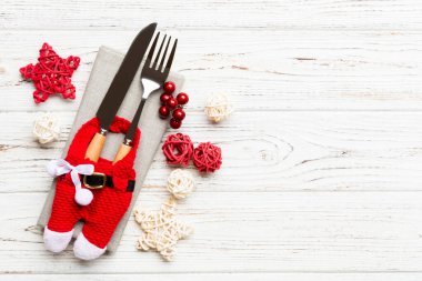 Tahta arka planda çatal ve bıçak seti. Noel süslemeleri ve fotokopi alanı olan oyuncaklar. Yeni yıl arifesi kavramı.