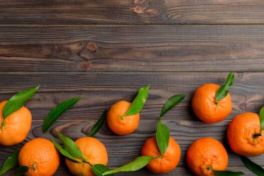 Renkli arkaplanda yeşil yaprakları, üst görünümü, metin için alanı olan bir sürü olgun mandalina..