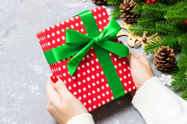 Bir kadının elinde hediye kutusuyla şenlikli çimento arka planına baktığı en iyi manzara. Firavun ağacı ve Noel süslemeleri. Yeni yıl zaman kavramı.