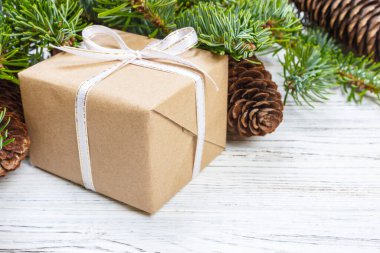 Çam kozalakları ve çam dalları ile karanlık rustik ahşap masa üzerinde Noel hediyeleri sarılmış. Metniniz için kopya alanı ile.