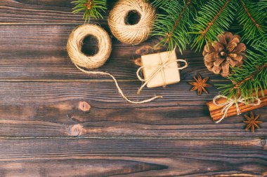 Noel arkaplanı ya da bayram tebrik kartı. Noel hediyesi kutusunda köknar ağacı dalı ve ahşap masa süsleri var. Kopyalama alanı olan üst görünüm. Ayarlanmış.