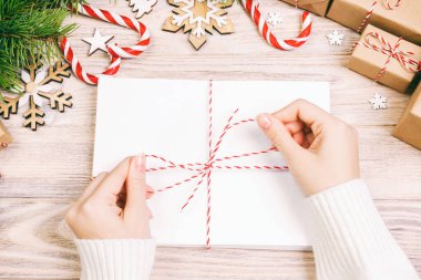 İple bağlanmış bir sürü zarf. Zarflı ünlü ellerin yakın çekim görüntüsü. Çam kozalakları ve noel süsü eski ahşap masa, masa. Ayarlanmış.