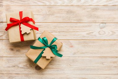 wrapped christmas or other holiday handmade present in paper with colored ribbon. Present box, decoration of gift on colourfull table, top view with copy space.