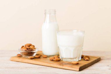 Cam şişedeki badem sütü ve renkli masada badem fıstığı. Üst görünüm vith kopyalama alanı.