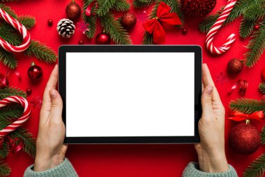 Evden Noel alışverişi, kadın elleri boş beyaz ekranlı tableti tutuyor. Kadın elinde tablet, boş ekran, Noel ağacı ve arka planda hediyeler..
