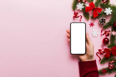 Mesaj atmak için yeri olan bir Noel modeli. Noel reklamı, uygulama şablonu. Masa arkasında boş ekran olan el ele tutuşan telefon. Mutlu yıllar ve Xmas Flat.