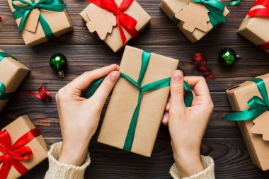 Kadınlar Noel tatili için sürpriz hediyeler hazırlıyor. İş yerinde el aletleri ve manzarayla oturuyor. Renkli masada Noel hediyesini paketleyen kadın..