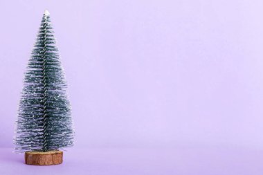 One small Christmas tree on colored background. new year decoration with copy space.