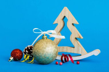 Christmas ball with decorative wooden tree on colored background. decoration bauble with ribbon bow with copy space.