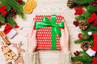 Elinde hediye kutusuyla neşeli tahta arka planda gezen bir kadının en iyi görüntüsü. Firavun ağacı ve Noel süslemeleri. Yeni yıl zaman kavramı.