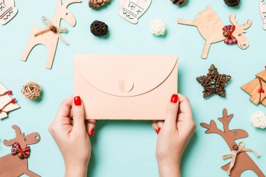 Bayram süslemelerinden yapılmış mavi arka planda bir zarf tutan kadının üst görüntüsü. Noel zamanı konsepti.