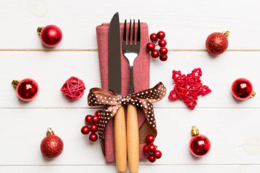 Tahta arka planda çatal ve bıçak seti. Noel süslemeleri ve fotokopi alanı olan oyuncaklar. Yeni yıl arifesi kavramı.