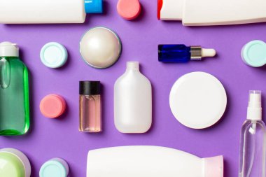 Renkli arka plandaki kozmetik ürünleri için farklı boyutlarda şişeler ve kavanozlar. Fotokopi alanı ile yüz ve vücut bakımı kavramı.