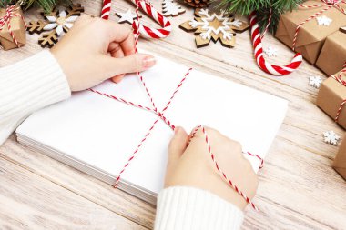 Birçok zarf ip ile bağladılar. Yakın çekim yukarıdan famale el ile zarf. Çam koniler ve Noel dekorasyonu eski ahşap tablo, Resepsiyon.