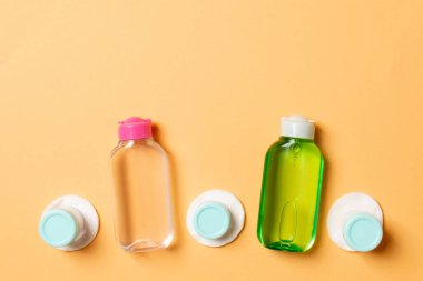 Yüz bakımı için en iyi bakış açısı: şişeler ve kavanozlar dolusu tonik, su, krem, renkli arka planda pamuk pedleri. Fikirleriniz için boş midye içeren vücut bakım konsepti.