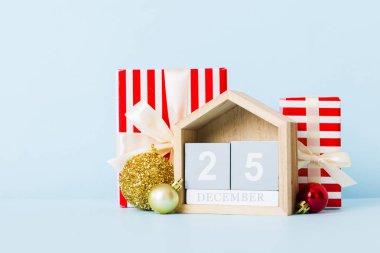 25 december. Christmas composition on colored background with a wooden calendar, with a gift box, toys, bauble copy space.