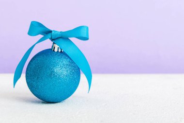 Christmas ball on colored background. decoration bauble with ribbon bow with copy space.