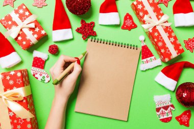 Kadın elinin yeşil arka planda notlar alırken üst görüntüsü. Yeni yıl süslemeleri ve oyuncakları. Noel zamanı konsepti.