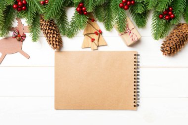 En tepedeki köknar ağacı manzarası, yeni yıl süslemeleri ve tahta arka plandaki defter. Kopya alanı ile Noel kavramı.