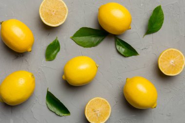 Renkli arka planda yeşil yapraklı taze limonlar, üst görünüm, metin için boşluk.