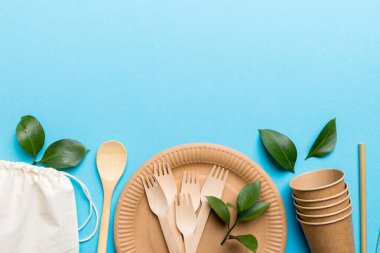 Açık beyaz masa arkaplanındaki boş, tek kullanımlık çevre dostu tabaklar, bardaklar, çatal bıçaklar. Üst Manzara. Biyo-çözünebilir el yapımı yemekler. Geri dönüşüm konsepti. Yakın plan..