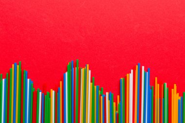 Renkli arka planda renkli plastik pipetler, düz yatış. Metin için Boşluğu Kopyala.