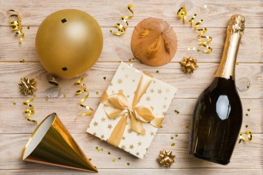 Renkli arka planda şampanya şişesi hediye paketi kurdeleleri ve konfetilerin düz kompozisyonu vardı. Düz konum, üst görünüm tatil konsepti.
