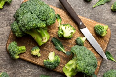 Tahta kesme tahtasının üzerinde bıçakla taze yeşil brokoli. Brokoli lahana yaprakları. Hafif arkaplan. Düz yatıyordu.