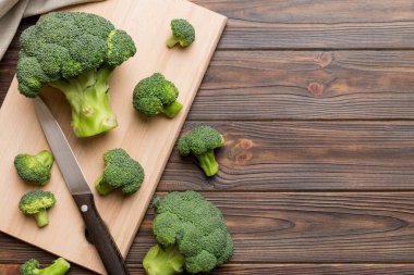 Tahta kesme tahtasının üzerinde bıçakla taze yeşil brokoli. Brokoli lahana yaprakları. Hafif arkaplan. Düz yatıyordu.