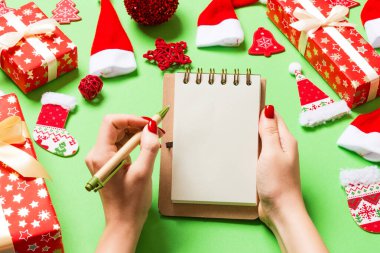 Kadın elinin yeşil arka planda notlar alırken üst görüntüsü. Yeni yıl süslemeleri ve oyuncakları. Noel zamanı konsepti.
