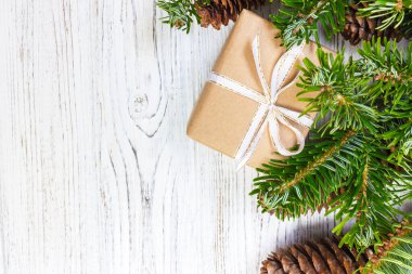 Çam kozalakları ve çam dalları ile karanlık rustik ahşap masa üzerinde Noel hediyeleri sarılmış. Metniniz için kopya alanı ile.