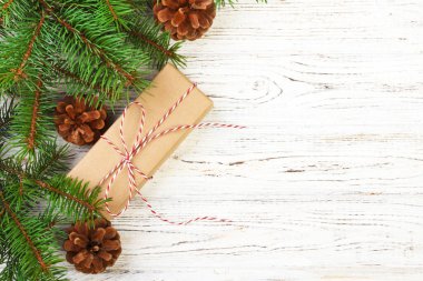 Çam kozalakları ve çam dalları ile karanlık rustik ahşap masa üzerinde Noel hediyeleri sarılmış. Metniniz için kopya alanı ile.