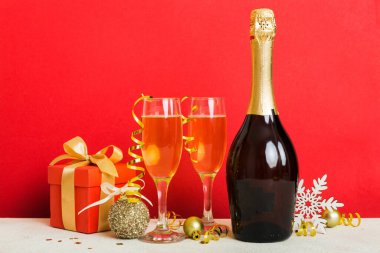 Champagne bottle with confetti, glasses and christmas decor on colored holiday background. Flat lay New Year decorations.